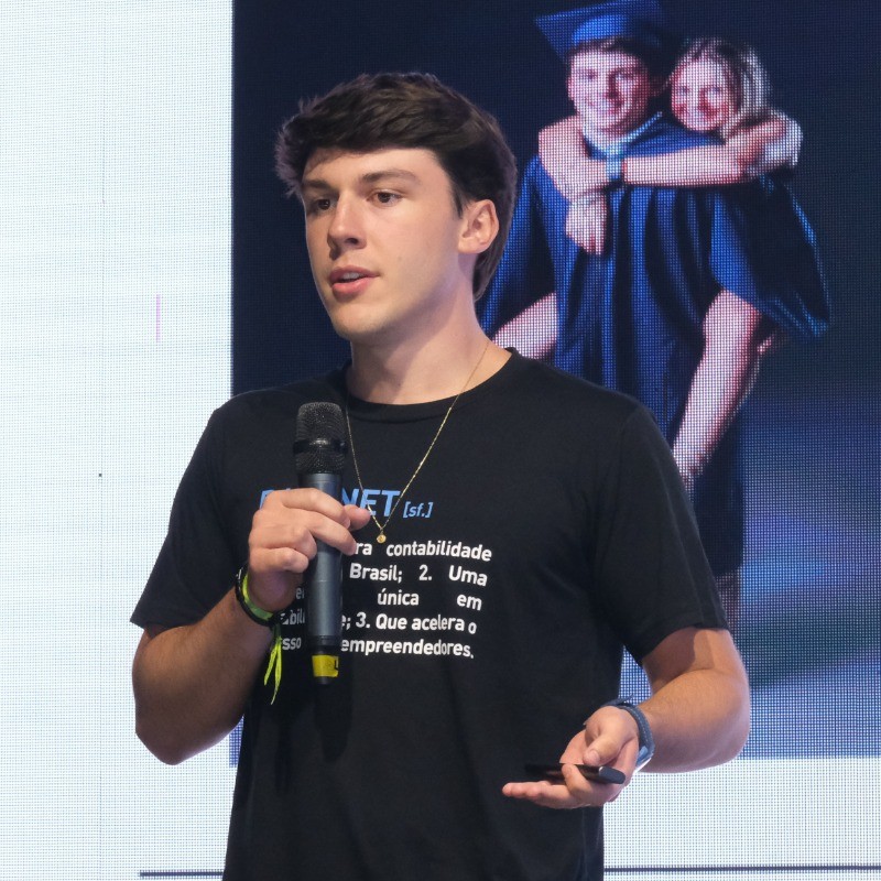 Gui on stage, holding a microphone and presenting